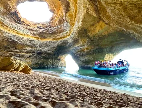 Barco à procura de golfinhos no passeio às Grutas de Benagil com observação de golfinhos